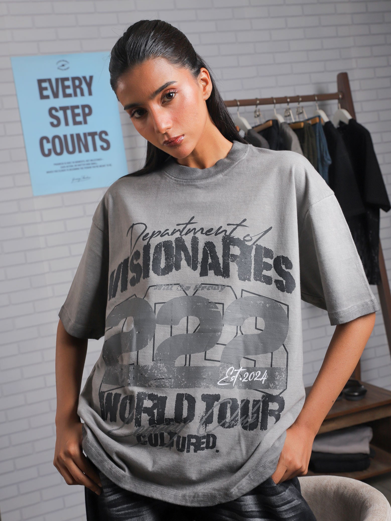 Female model leaning forward in Visionaries 222 t-shirt, styled with slick hair and a minimalistic streetwear backdrop.