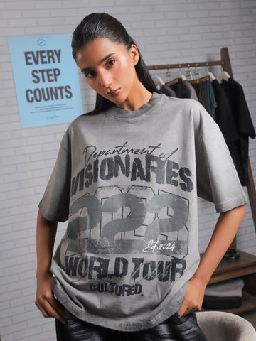 Female model leaning forward in Visionaries 222 t-shirt, styled with slick hair and a minimalistic streetwear backdrop.