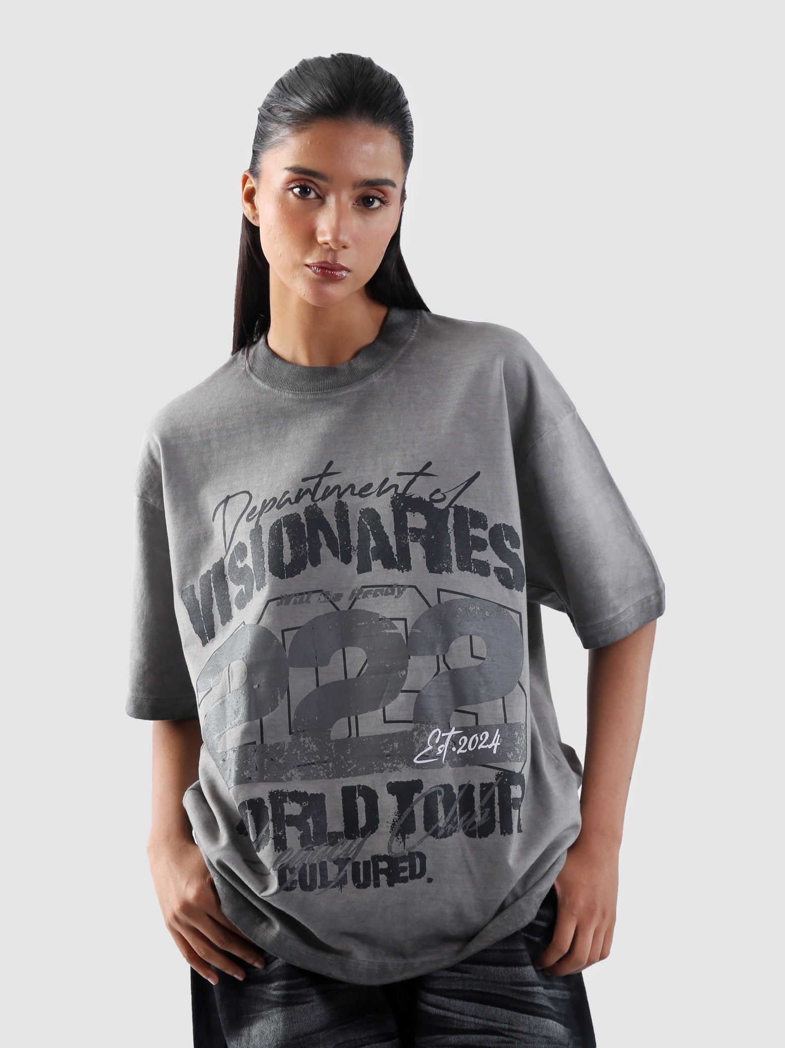 Medium close-up of female model wearing oil-washed Cultured t-shirt with distressed typography and streetwear attitude.