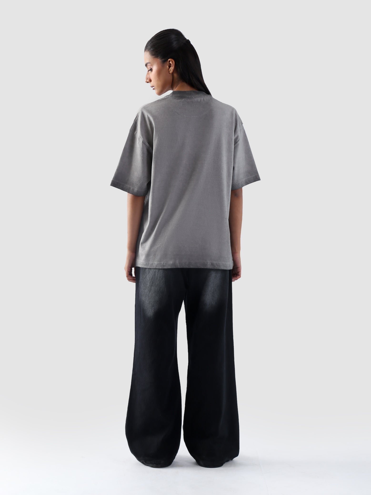 Back profile of the Oil Fade t-shirt worn by female model, showcasing plain wash and relaxed fit silhouette.